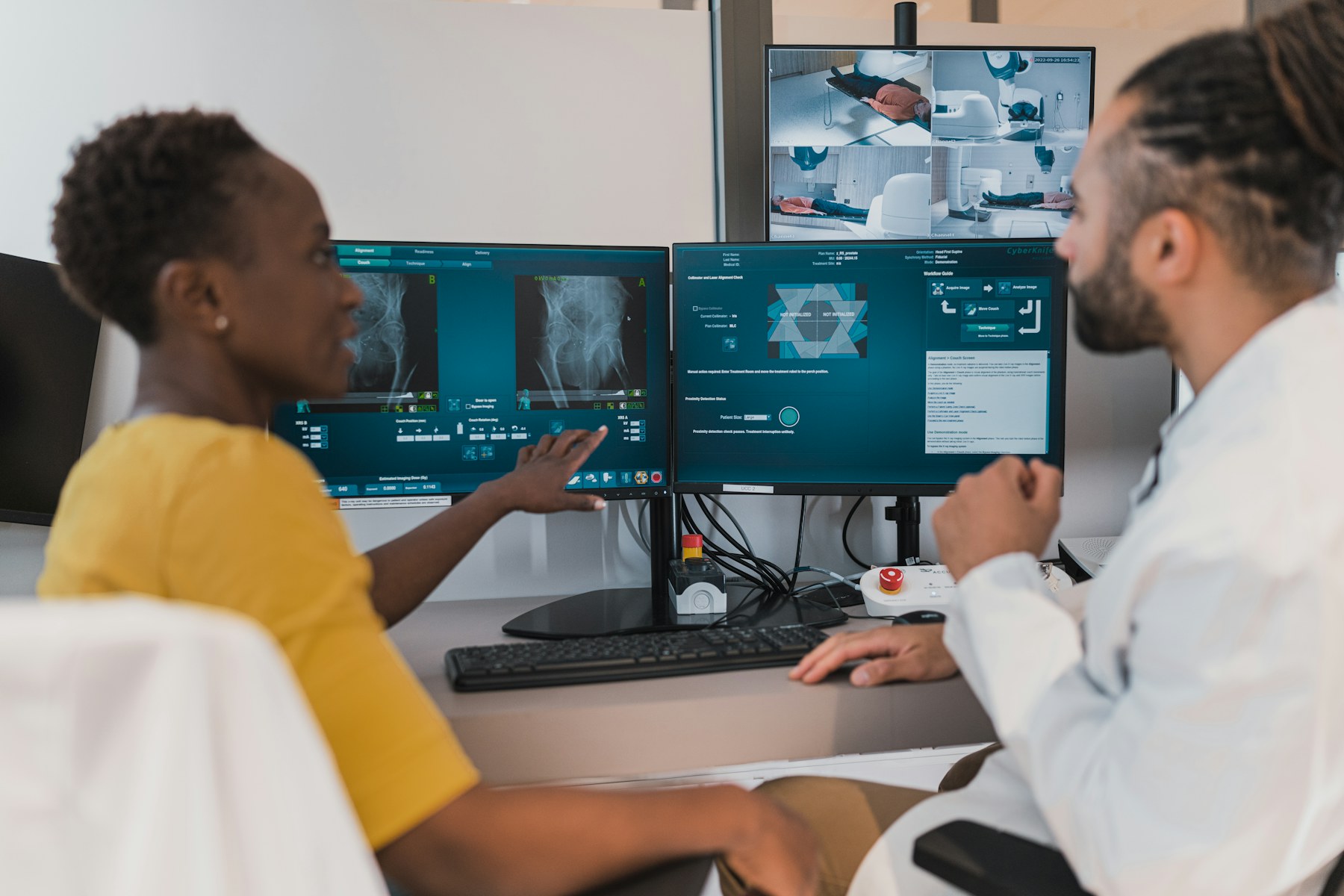 Two clinicians coordinating a digital imaging workflow at multiple monitors